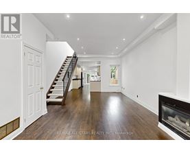 A spacious living room with a fireplace and a staircase.
