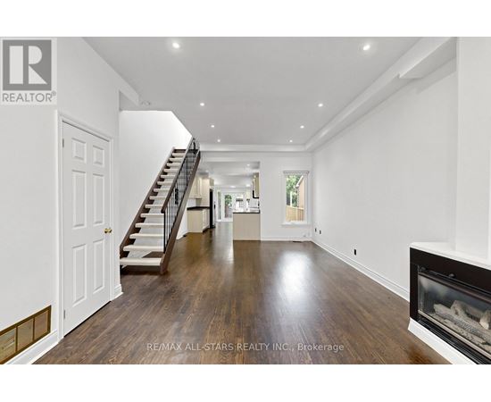 A spacious living room with a fireplace and a staircase.