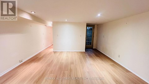 A spacious room with wooden flooring and white walls.