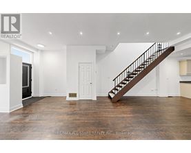 A spacious room with a wooden staircase and white walls.