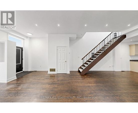 A spacious room with a wooden staircase and white walls.