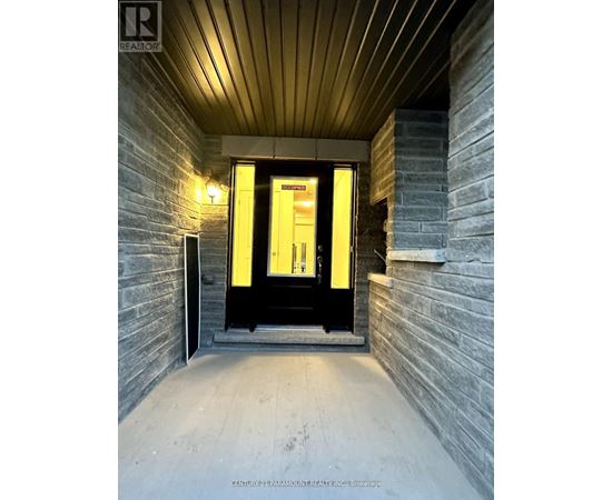 A hallway with a black door and a light on the wall.