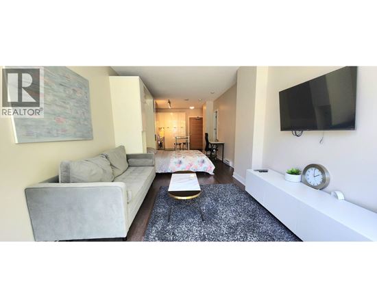 A living room with a grey couch and a coffee table in front of a TV.