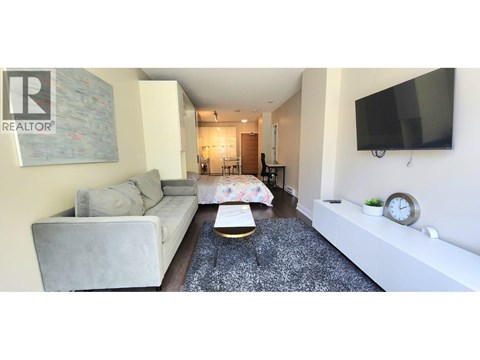 A living room with a grey couch and a coffee table in front of a TV.