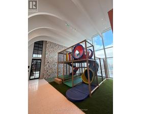 A colorful playground structure is situated in a brightly lit room with a view of the outside.