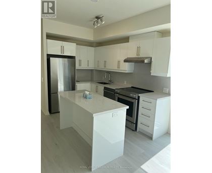 A modern kitchen with white cabinets and a stainless steel refrigerator.