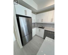 A modern kitchen with a black refrigerator and white cabinets.