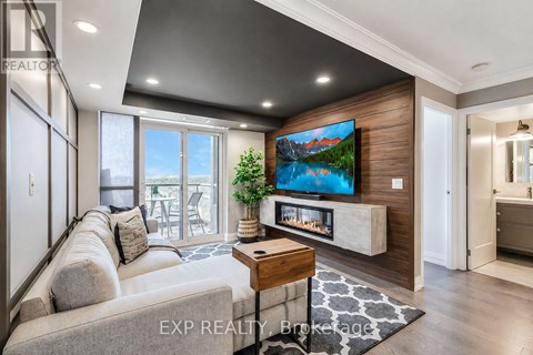 A modern living room with a large grey sofa and a flat screen TV mounted on a wooden wall.