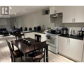 A kitchen with a table and chairs in the foreground and a stove top oven in the background.