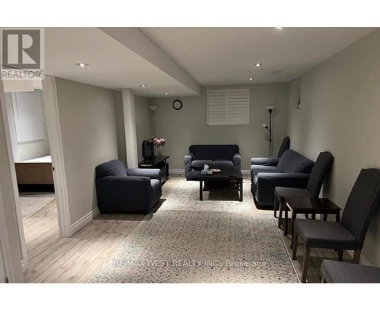 A living room with a grey sofa and black chairs.