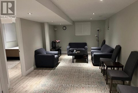 A living room with a grey sofa and black chairs.