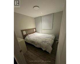 A bedroom with a bed, nightstand, and window with blinds.