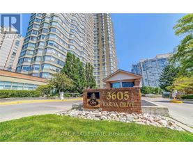 A sign for 3605 Kariya Drive is in front of a tall building.