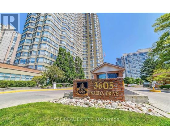 A sign for 3605 Kariya Drive is in front of a tall building.