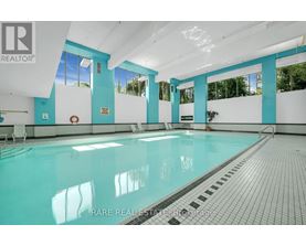 A swimming pool inside a building with a person standing on the side.