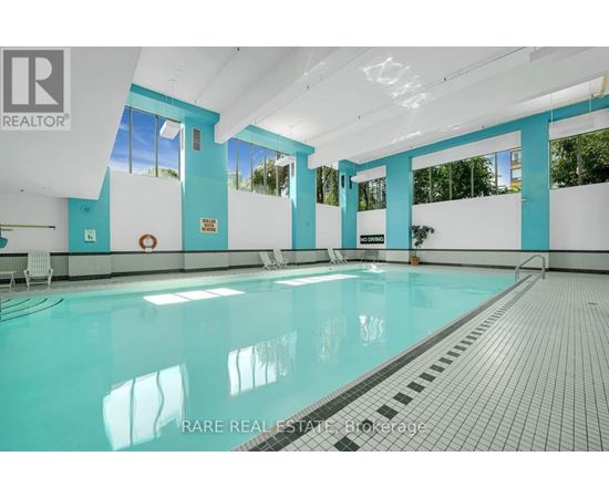 A swimming pool inside a building with a person standing on the side.