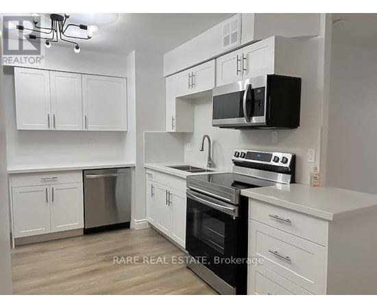 A kitchen with white cabinets and a black microwave.