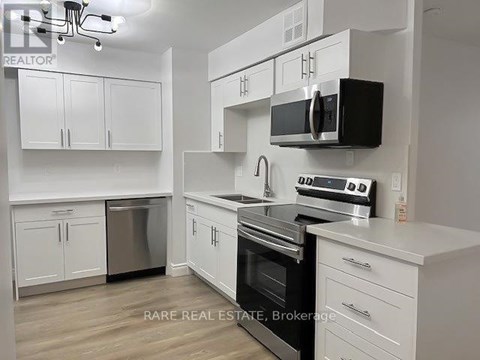A kitchen with white cabinets and a black microwave.