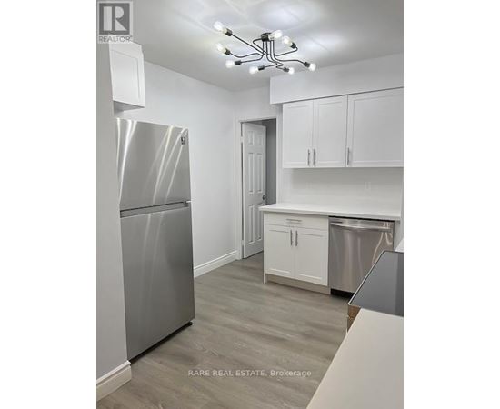 A kitchen with a stainless steel refrigerator and cabinets.