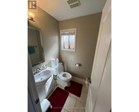 A bathroom with a toilet, sink, and mirror.