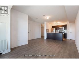 A spacious living room with a kitchenette in the background.