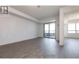 A spacious room with wooden flooring and a sliding glass door.