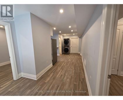 A hallway with wood flooring and white walls.