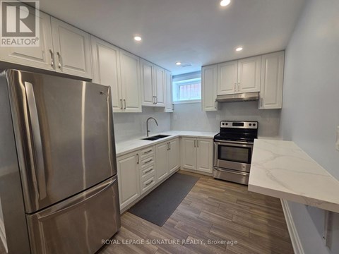 A kitchen with a stainless steel refrigerator and a stove top oven.
