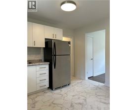 A kitchen with a refrigerator, cabinets, and a marble floor.