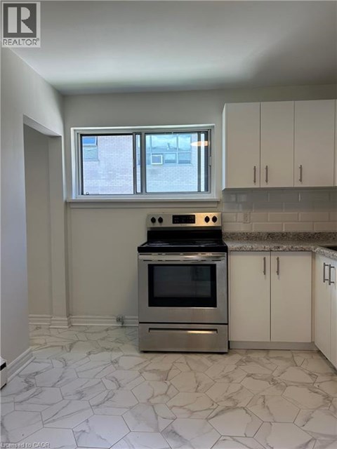 A kitchen with a stove top oven and a window.