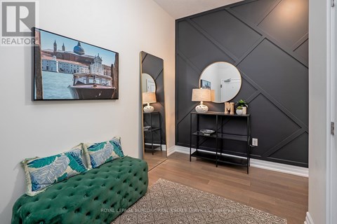 A living room with a green couch and a painting on the wall.