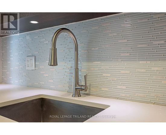 A modern kitchen with a sink and a wall of tiles.