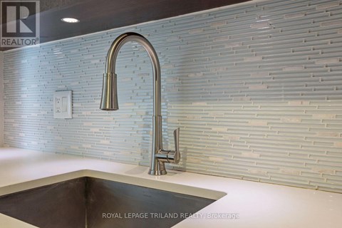 A modern kitchen with a sink and a wall of tiles.