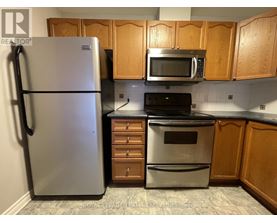 A kitchen with a refrigerator, microwave, oven, and cabinets.