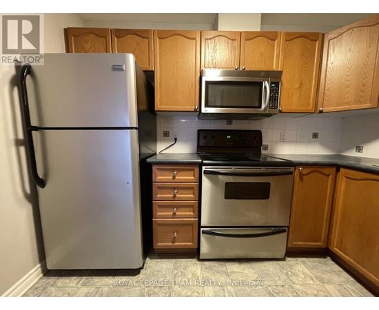 A kitchen with a refrigerator, microwave, oven, and cabinets.