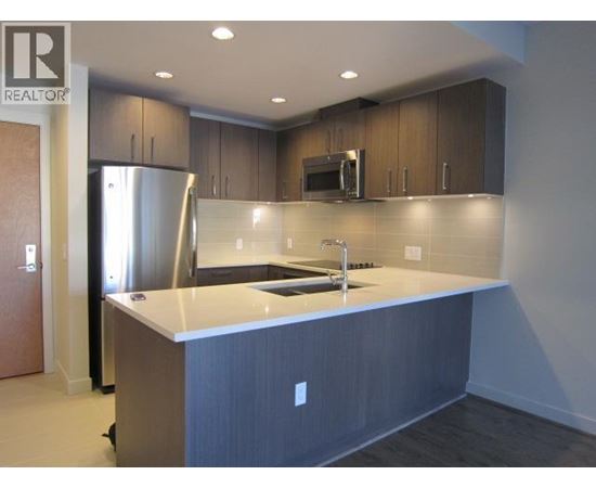 A kitchen with a refrigerator, microwave, and sink.