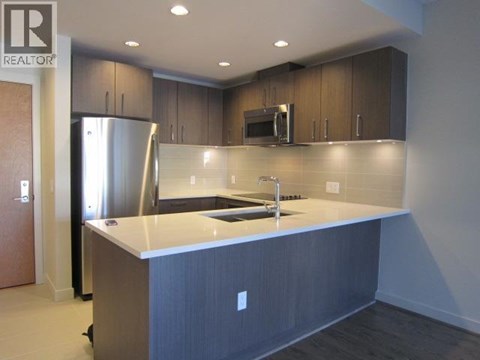 A kitchen with a refrigerator, microwave, and sink.