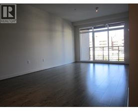 A large empty room with wooden floors and a window with blinds.