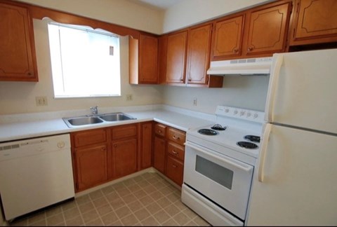 A kitchen with white appliances and wooden cabinets.