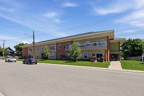 A street view of a residential area with apartment buildings and cars parked on the side of the road.