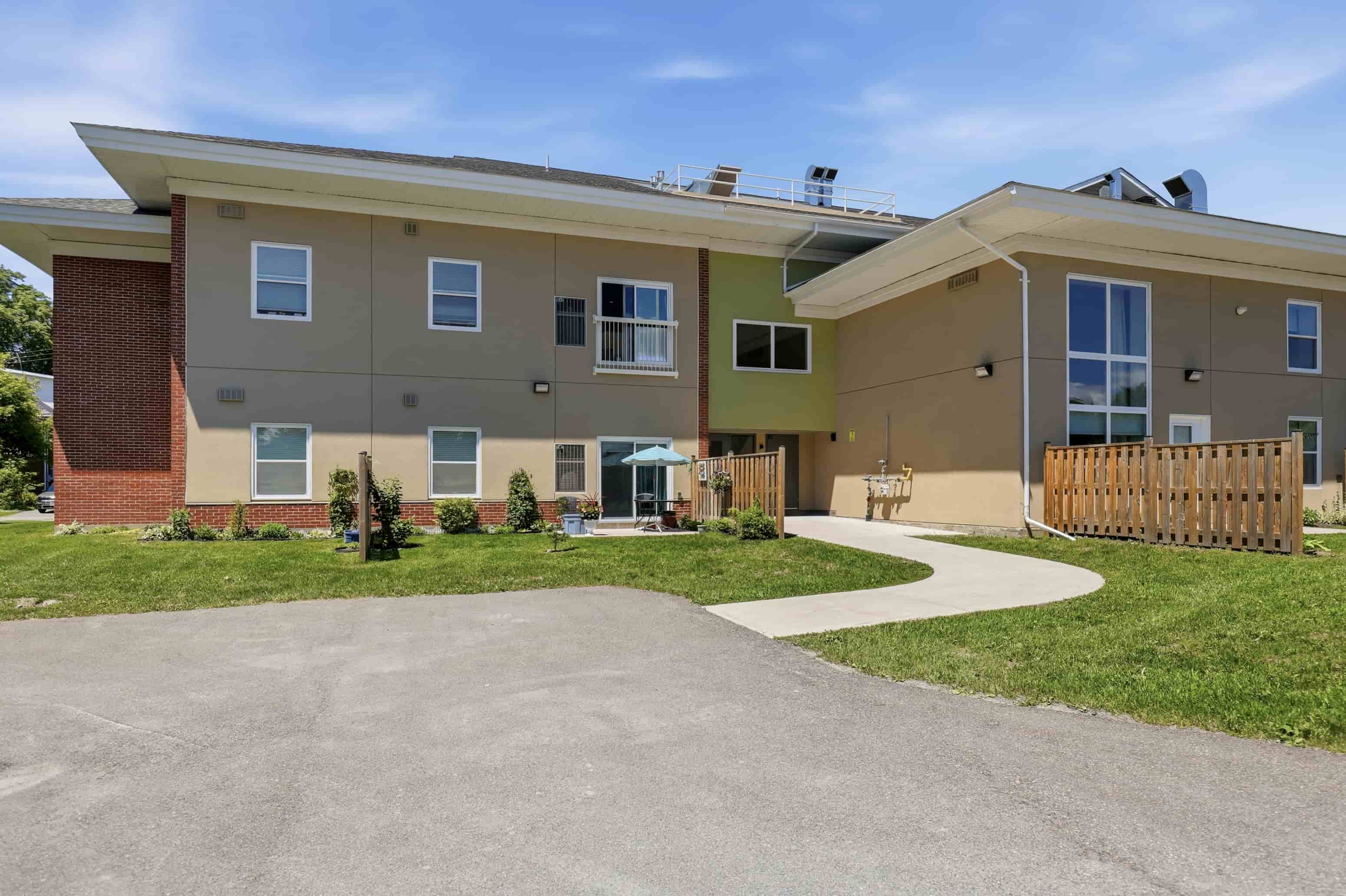 A modern two-story apartment building with a driveway in front.