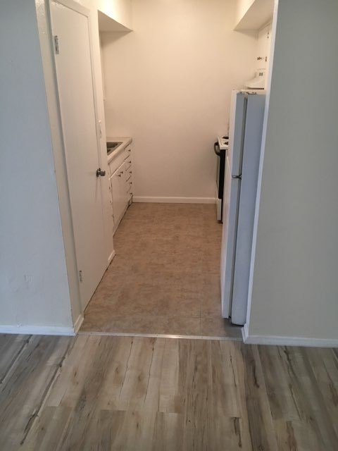 A kitchen with a white fridge and white cabinets.