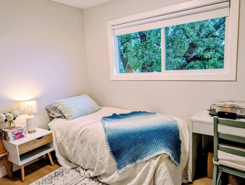 A bedroom with a bed covered in a blue and white blanket.