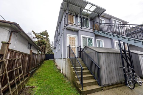 A grey building with a bicycle leaning against the railing.