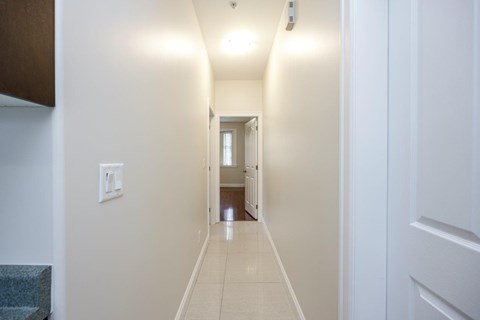 A long hallway with white walls and a tiled floor.