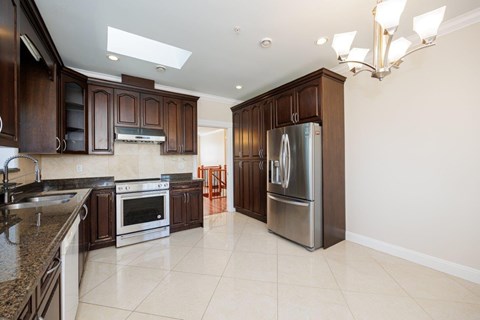 A kitchen with brown cabinets and a stainless steel refrigerator.