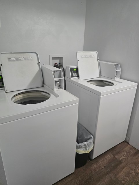 Two white front loading washing machines in a laundry room.