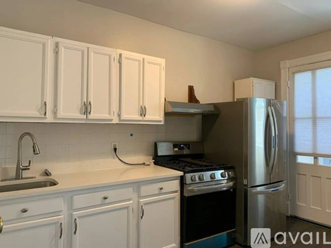 A kitchen with white cabinets and a stainless steel refrigerator.