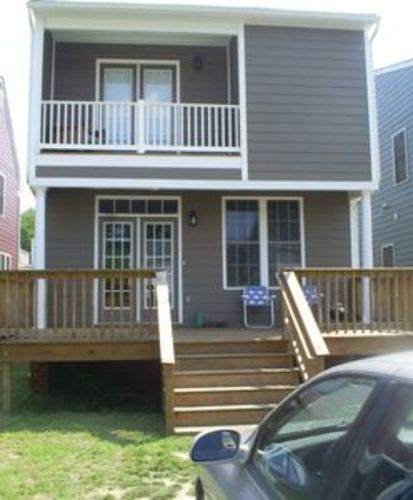 A house with a balcony and a car parked in front.