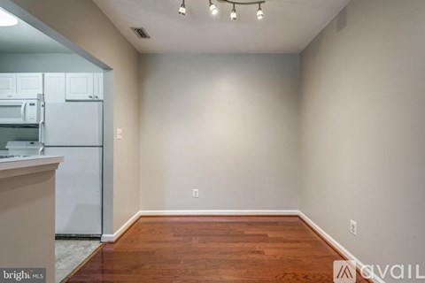 A kitchen with a refrigerator and a wooden floor.